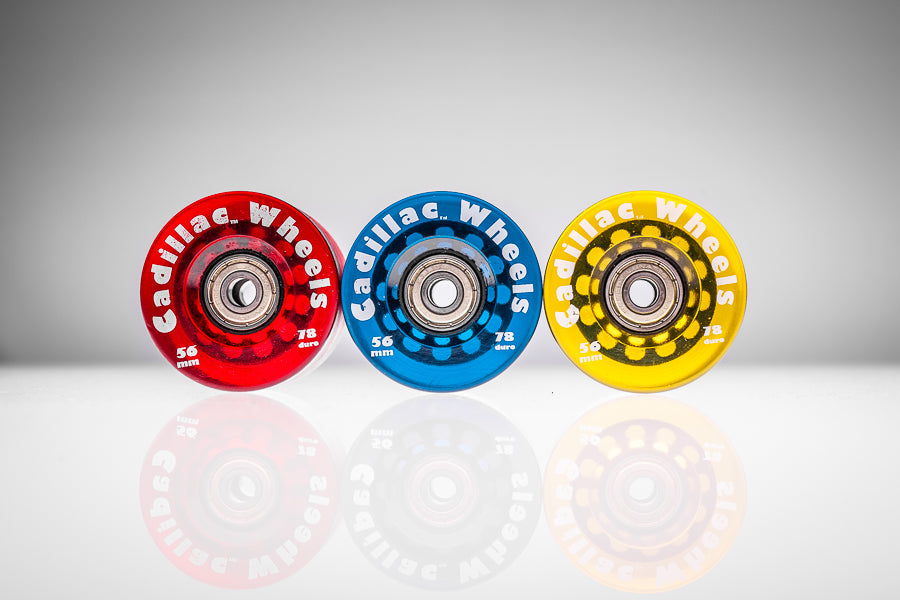 Three Santoro Fabworx Cadillac crash bar wheels in red, blue and gold with reflections and Cadillac Wheels branding