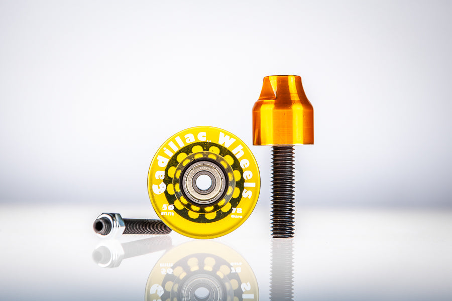 Yellow Santoro Fabworx Cadillac crash bar wheel with gold mount and bolt on a reflective surface