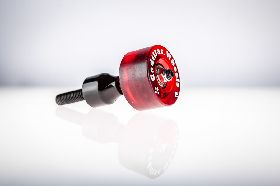 Red Santoro Fabworx Cadillac crash bar wheel with black mount and bolt, side view on a reflective surface